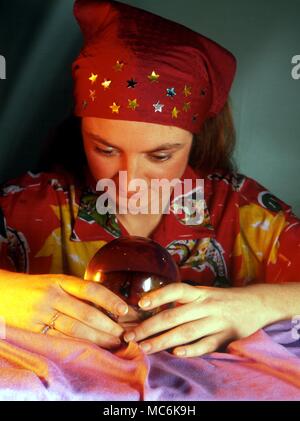 Fissando lo sguardo di cristallo. Giovane donna utilizzando una sfera di cristallo per predire il futuro. Foto Stock