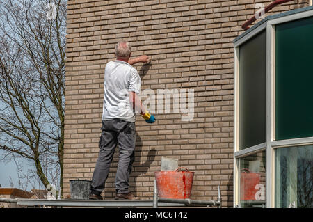 Un muratore è di aggiungere i mattoni di un muro di una casa residenziale Foto Stock