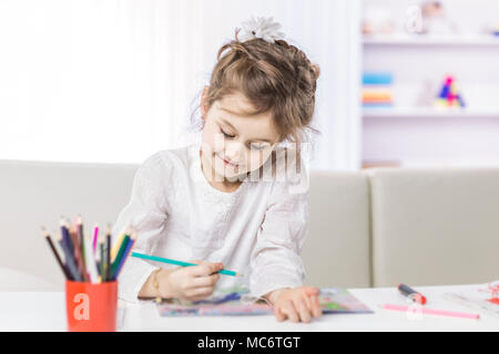 Bambina di cinque anni disegna con matite colorate seduta a tavola nel vivaio Foto Stock