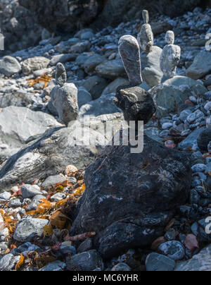 Rocce di bilanciamento scultura fatta di una roccia equilibrato sulla parte superiore di un altro, tutte di dimensioni diverse creato a mano su una spiaggia rocciosa al di sotto di Sant Agnese, Cornwall. Foto Stock