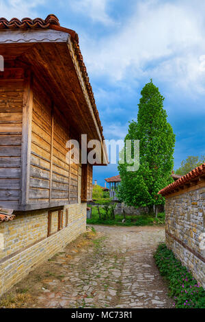 Stretta viuzza acciottolata in Zheravna, Bulgaria - riserva architettonica di case rustiche dalla nazionale bulgara per periodo di rinascita Foto Stock