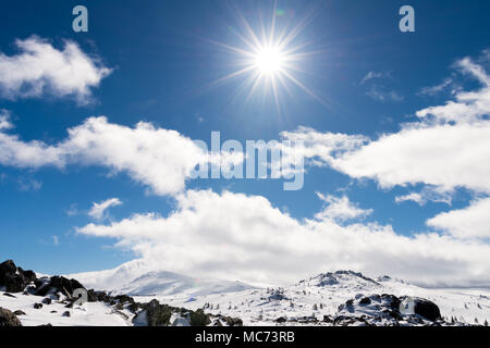 Paesaggio invernale delle montagne innevate con il sole che splende sopra le nuvole e raggi di sole nel cielo blu, Vitosha national park, Bulgaria Foto Stock