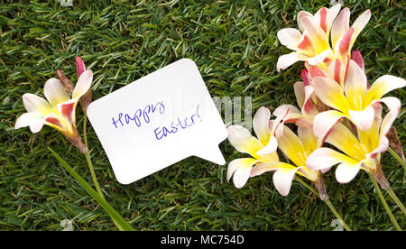 Nota Nella forma di una chat bolla con parole Buona Pasqua! E fiori sul prato verde. Foto Stock