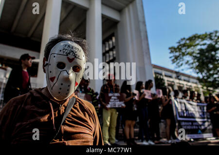 Quezon City, Filippine. Xiii Apr, 2018. Un uomo che indossa una maschera sta con gli studenti in nero per protestare contro le Filippine Presidente Rodrigo Duterte alla violazione dei diritti umani e la dittatura presso l'Università delle Filippine in Quezon City il venerdì. I manifestanti, convenuti da vari collegi, ha portato le bandiere e una bara a simboleggiare la morte della democrazia e dei diritti dell'uomo sotto l'amministrazione Duterte. Credito: Basilio H. Sepe/ZUMA filo/Alamy Live News Foto Stock