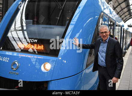 13 aprile 2018, Germania, Wiesbaden: di Hesse Economia e ministro dei Trasporti, Tarek Al-Wazir dell'Alleanza 90/Partito Verde sorge sulla piattaforma accanto ad una cella a combustibile alimentata a treno communter del costruttore francese Alstrom. Il trasporto regionale associazione 'Rhein-Main-Verkehrsverbund' vuole sostituire il treno diesel motori che sono stati la manutenzione di quattro non elettrificate linee secondarie nella regione Taunus. Foto: Arne Dedert/dpa Foto Stock