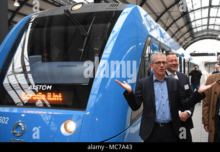 13 aprile 2018, Germania, Wiesbaden: di Hesse Economia e ministro dei Trasporti, Tarek Al-Wazir dell'Alleanza 90/Partito Verde sorge sulla piattaforma accanto ad una cella a combustibile alimentata a treno communter del costruttore francese Alstrom. Il trasporto regionale associazione 'Rhein-Main-Verkehrsverbund' vuole sostituire il treno diesel motori che sono stati la manutenzione di quattro non elettrificate linee secondarie nella regione Taunus. Foto: Arne Dedert/dpa Foto Stock