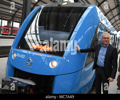 13 aprile 2018, Germania, Wiesbaden: di Hesse Economia e ministro dei Trasporti, Tarek Al-Wazir dell'Alleanza 90/Partito Verde sorge sulla piattaforma accanto ad una cella a combustibile alimentata a treno communter del costruttore francese Alstrom. Il trasporto regionale associazione 'Rhein-Main-Verkehrsverbund' vuole sostituire il treno diesel motori che sono stati la manutenzione di quattro non elettrificate linee secondarie nella regione Taunus. Foto: Arne Dedert/dpa Foto Stock