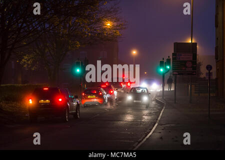 I veicoli che viaggiano lungo una strada suburbana di notte. Foto Stock