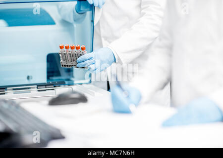 Assistente di laboratorio test di riempimento tubi dentro la macchina analizzatore Foto Stock