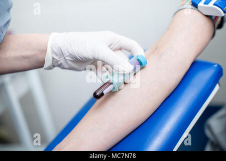 Assistente di laboratorio prelievo di sangue con capsula a depressione per test dalla vena del braccio in laboratorio Foto Stock