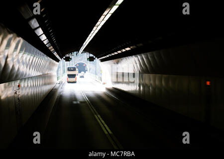 Strada urbana con la linea di demarcazione e segni passando attraverso il tunnel sotterraneo collegato con ponte di cemento. I mezzi di trasporto pubblico e delle vetture su strada. Foto Stock