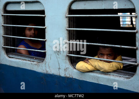 Ragazzo e una ragazza del peering dalla finestra sbarrata di un treno indiano, Mumbai legato Foto Stock