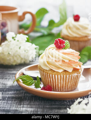 Delicati tortini alla vaniglia con crema di lamponi e sul legno scuro dello sfondo. Foto Stock