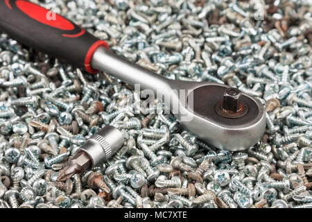 Cacciavite giacente su un mucchio di viti. Close-up Foto Stock