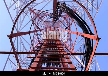 La fotografia offre una prospettiva verso l'alto della struttura interna di una torre di telecomunicazioni. L'immagine rivela la complessa struttura in acciaio che c Foto Stock