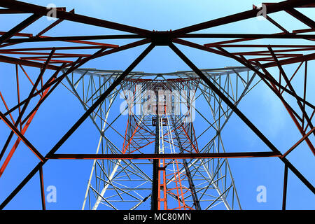 La fotografia offre una prospettiva verso l'alto della struttura interna di una torre di telecomunicazioni. L'immagine rivela la complessa struttura in acciaio che c Foto Stock