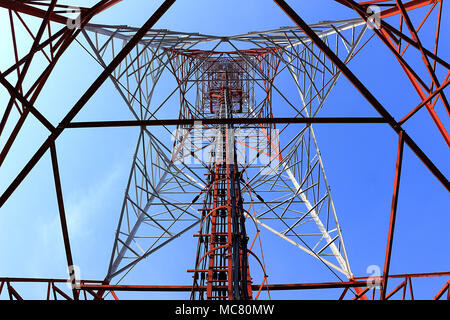 La fotografia offre una prospettiva verso l'alto della struttura interna di una torre di telecomunicazioni. L'immagine rivela la complessa struttura in acciaio che c Foto Stock