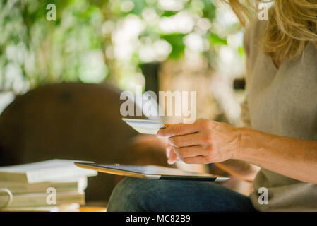 Donna con tavoletta digitale e una carta di credito, ritagliato Foto Stock