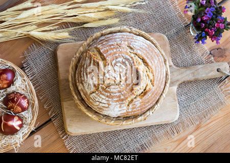 Una pagnotta di pane di pasta acida in un cesto su un tavolo di legno Foto Stock