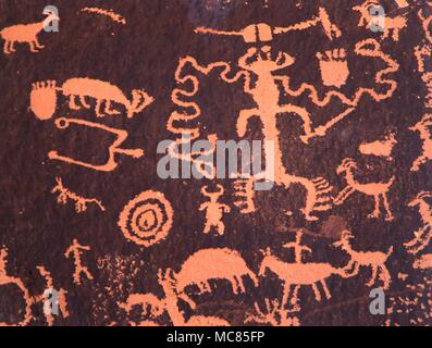 - Petroglifi Indiani del Nord America. Intagliato e dipinto di disegni (incisioni rupestri) raffiguranti divinità, medecine-uomini, bovini, i serpenti o linee di serpente e una varietà di altri simboli, incluso il "stampe' di piedi umani. Queste incisioni rupestri sono sul cosiddetto Newspaper Rock, nel deserto dello Utah. Foto Stock