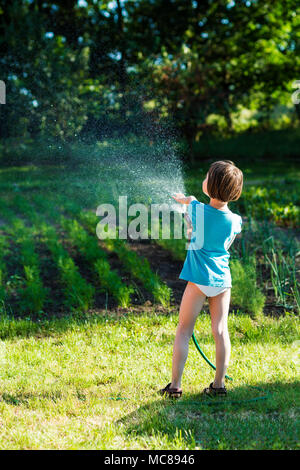 Bambina bambino verdure di irrigazione nel piccolo giardino. Foto Stock