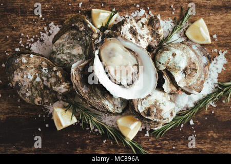 Open shell oyster con limone e sale su una tavola di legno Foto Stock