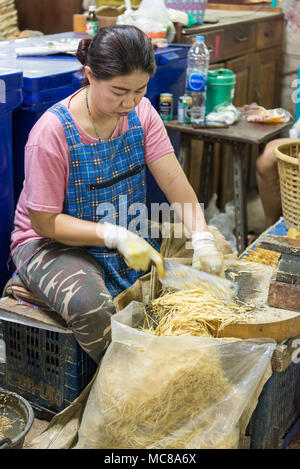 Una donna si prepara lo zenzero nel mercato dei fiori a Bangkok in Tailandia Foto Stock