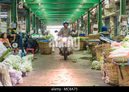 Un uomo che cavalca una moto in una passerella di collegamento attraverso il mercato dei fiori a Bangkok in Tailandia Foto Stock