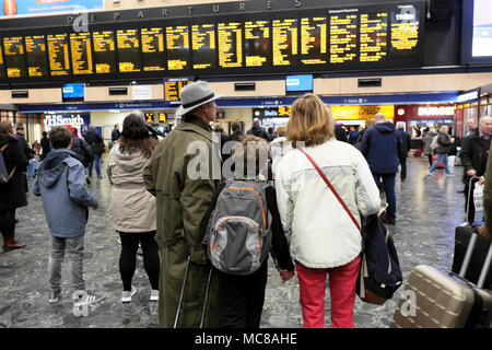 Vista posteriore della famiglia in piedi sull'atrio che controlla il Partenza per il treno con partenza alla stazione di Euston A Londra Regno Unito KATHY DEWITT Foto Stock