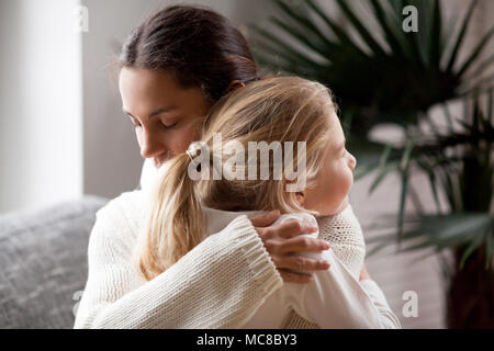 Madre amorevole abbraccio carino bambina, giovane donna abbracciando adottato il bambino che tiene stretto, sincere relazioni caldo tra mamma e figlia cuddlin Foto Stock