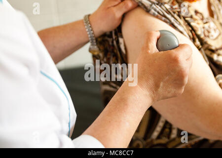 Il vecchio donna sta avendo diabetis sensore intelligente attaccata alla mano da un medico specialista Foto Stock
