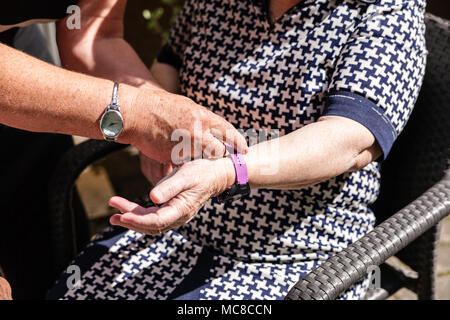Old womans è avente dispositivo indossabile smart guardare in casa di cura Casa di pensionamento. Foto Stock