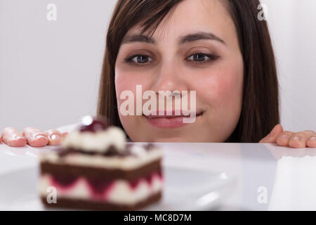 Giovane donna desiderio di mangiare fetta di torta leccare le sue labbra Foto Stock