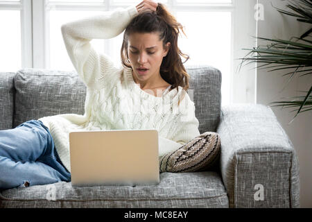 Scioccato giovane donna guardando lo schermo del computer portatile a casa spiacevolmente sorpreso dal messaggio di notifica di posta elettronica la lettura di cattive notizie on line sul debito, Foto Stock