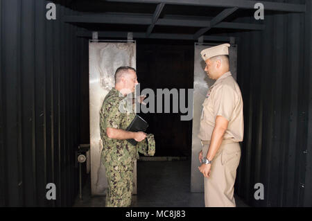 SANTA RITA, Guam (2 aprile 2018) posteriori Adm. James acque III, direttore sede marittima, U.S. Flotta del Pacifico, a sinistra illustra le funzionalità del sommergibile Naval Training Center Pacific distacco (NSTCP det) Guam mobile del trainer di estinzione, MT-1000, con Lt. Jeffrey Cornielle, NSTCP det Guam Officer in carica, durante un tour del training facility, 2 aprile. Le acque si è incontrato con i comandi della marina in Guam per discutere di manutenzione della nave e le capacità logistiche e di preoccupazioni. Foto Stock