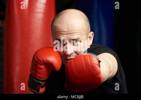 Close-up di uomo che fa la boxe punch su scuro dello sfondo della palestra Foto Stock