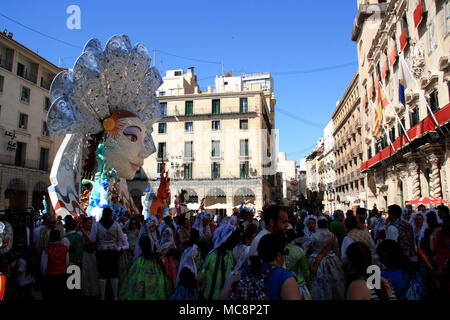 Tradizionalmente vestiti persone all'Hogueras de Festival di San Juan di Alicante in Spagna, la pubblicazione per una foto di fronte a un enorme polena Foto Stock
