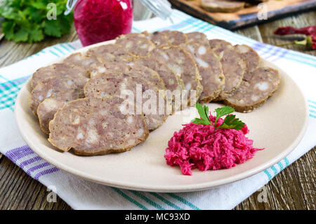 Fatto in casa salsiccia dietetici da fegato su un tavolo di legno. Salsiccia tagliata a pezzi su una piastra con salsa di rafano. Foto Stock