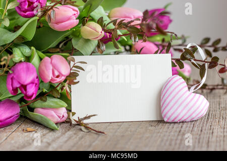 Bel bouquet di rosa e viola i tulipani con un cuore e una copia bianca spazio su uno sfondo di legno Foto Stock