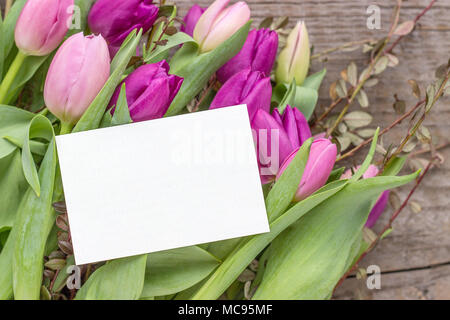 Bel bouquet di rosa e viola i tulipani con un bianco copia spazio su uno sfondo di legno Foto Stock