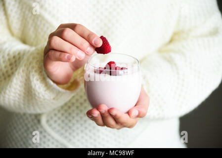 Ragazza detiene il bicchiere di latte o yogurt, kefir con lamponi. Sana e pulita di mangiare. Copia dello spazio. La prima colazione e snack. Il concetto di stile di vita Foto Stock