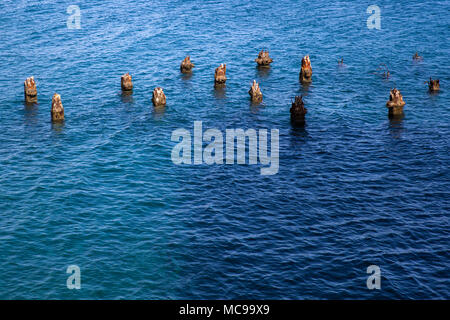 Resti di antiche colonne di legno in mare Foto Stock