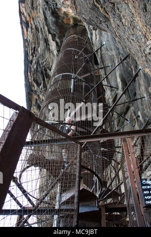 Redhead Tourist salendo le scale a spirale in corrispondenza di Lion Rock in Sigiriya, Sri Lanka Foto Stock