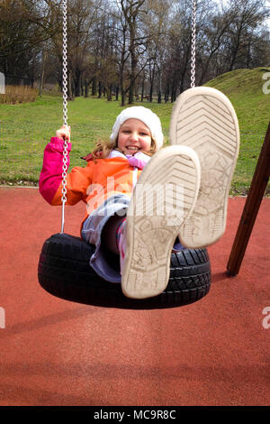 Bambino felice ragazza basculante in un parco giochi in un parco d'autunno. Foto Stock