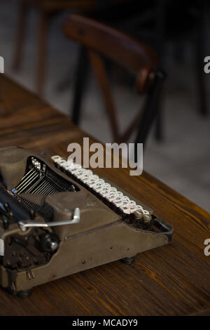 Vista posteriore e laterale colpo di una macchina da scrivere vintage su un tavolo di legno. Girato con profondità di campo ridotta. Composizione verticale. Foto Stock