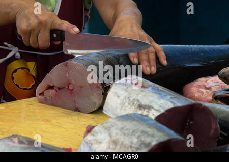 Close up mani femminili tenendo il coltello per affettare il pesce in preparazione per essere tagliato in filetti di salmone - outdoor mercato di frutti di mare Foto Stock