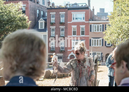 Il punto di vista di un giovane intrattenitore vestito da fantasma visto condurre un tour storico in un famoso cimitero di Boston durante la fine dell'estate. Foto Stock