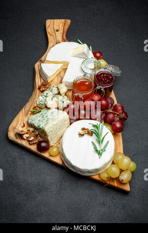 Vari tipi di formaggio e marmellata sul tagliere di legno Foto Stock