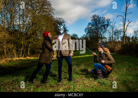 Due femmine vestiti in marcia le riprese tenendo l uomo nella maschera di coniglio Foto Stock