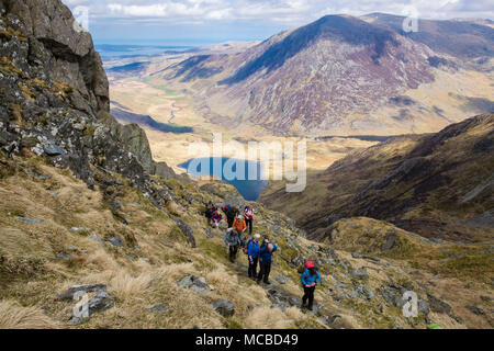 Gli escursionisti escursionismo fino Seniors cresta sopra Cwm Idwal con penna yr Ole Wen dietro nelle montagne del Parco Nazionale di Snowdonia. Ogwen, Conwy, Wales, Regno Unito, Gran Bretagna Foto Stock